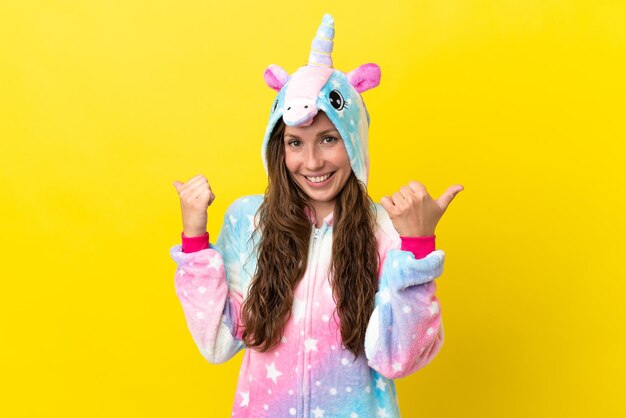 Girl with unicorn pajamas over isolated background with thumbs up gesture and smiling