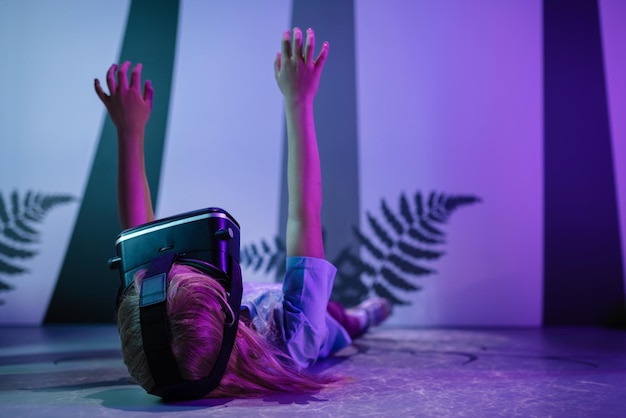 Photo girl with vr glasses laying on a floor fluorescent light effects
