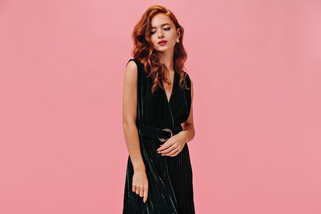 girl with wavy hair dresses in velvet outfit poses on isolated wall