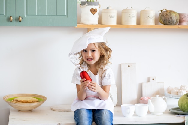 Girl with whisk in kitchen at home