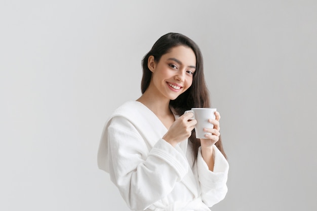 Girl with white cup in hands. Casual woman portrait with drink tea or coffe female indors home. Studio shot.