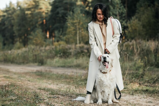 girl with white golden retriever dog on the forest path