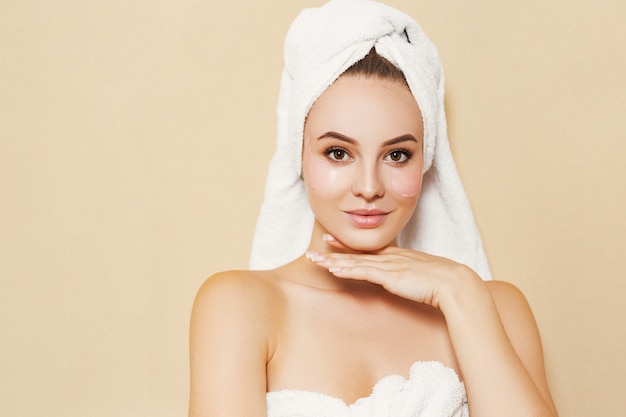 Girl with a white towel on her head on a beige background