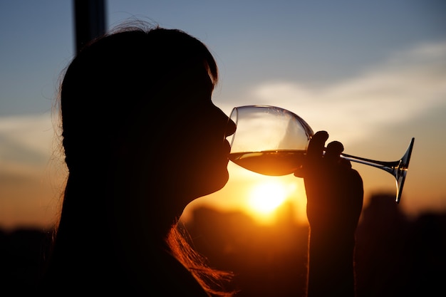 Girl with wine glass. Black silhouette.