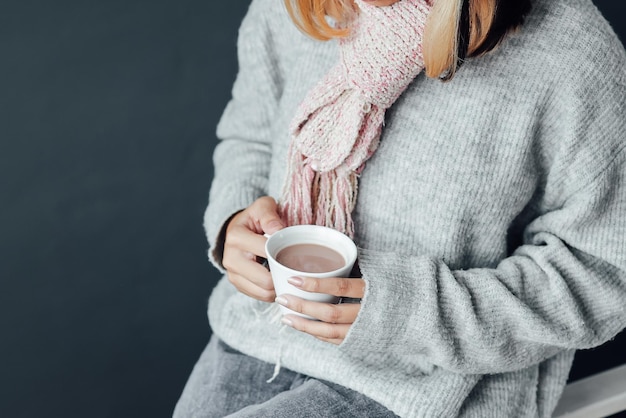 自宅で冬の季節にホットチョコレートのカップを楽しんでいる冬の服を着た女の子