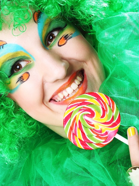 Girl with with creative make-up holds lollipop. Doll style.