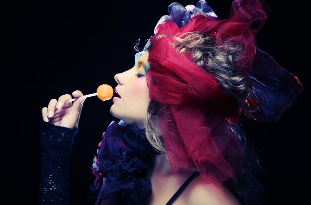 Girl with  with creative make-up holds  lollipop 