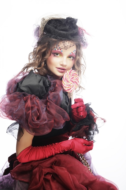 Girl with with creative make-up holds lollipop.