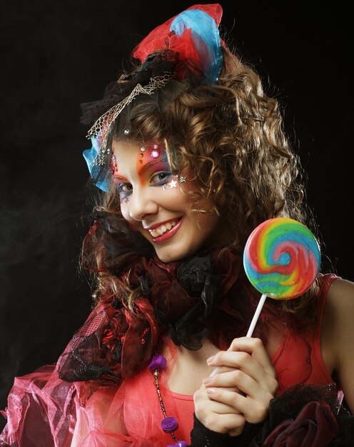 Photo girl with with creative makeup holds lollipop doll style