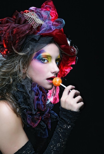 Girl with with creative makeup holds lollipop