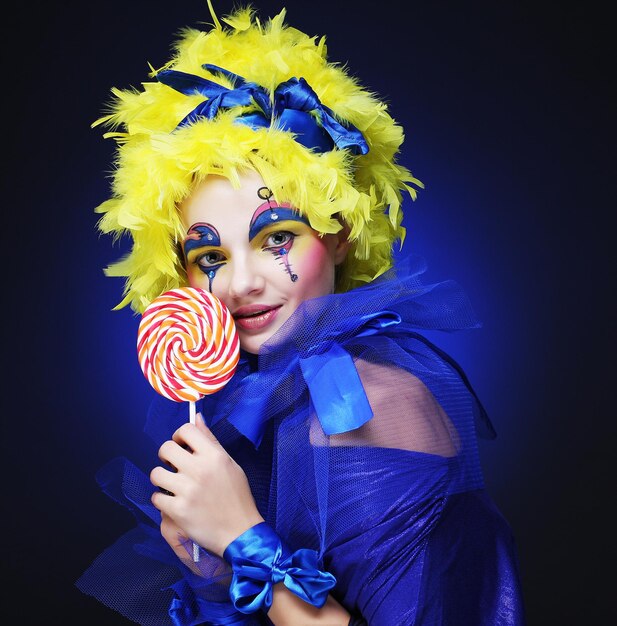 Girl with with creative makeup holds lollipop