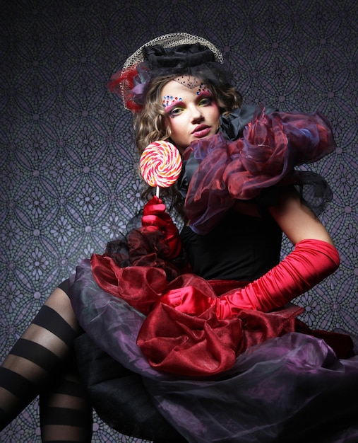 Girl with with creative makeup holds lollipop