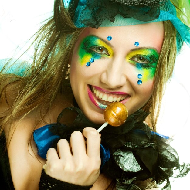 Girl with with creative makeup holds lollipop