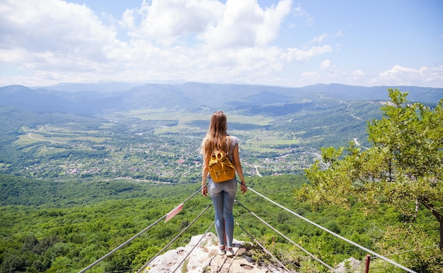 Una ragazza con uno zaino giallo in cima a una montagna