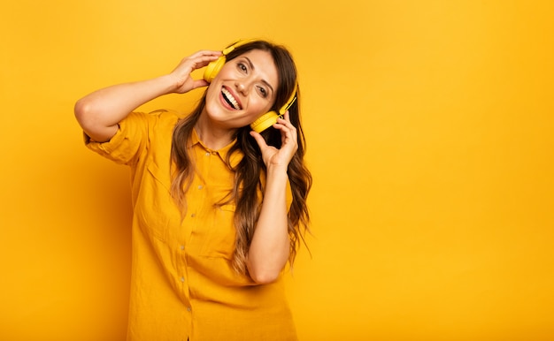 Ragazza con un auricolare giallo ascoltando musica e ballando