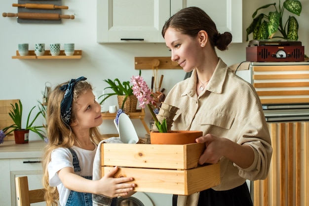 Ragazza e donna trapiantano fiori e piante da interno che tengono insieme una scatola con bulbi giacinti