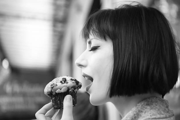 관능적인 얼굴을 가진 소녀 또는 여성은 프랑스 파리에서 블루베리 머핀을 먹습니다. 배고픈 유혹 식욕 개념 디저트 음식 스낵 패스트리