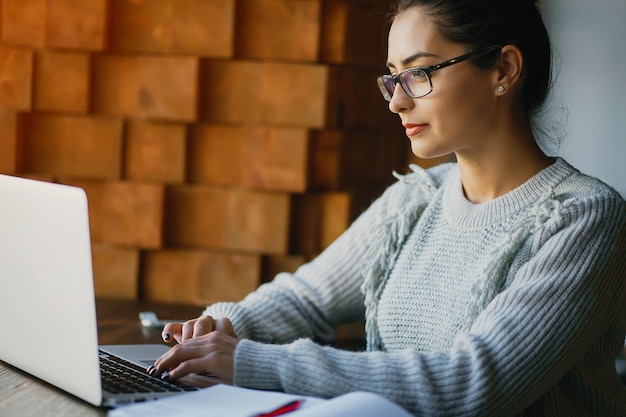 Ragazza che lavora su un computer portatile in un ristorante