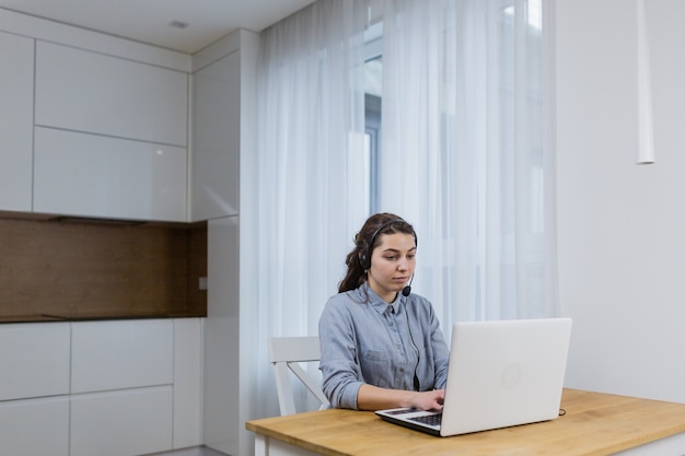 Girl working online with laptop using headset