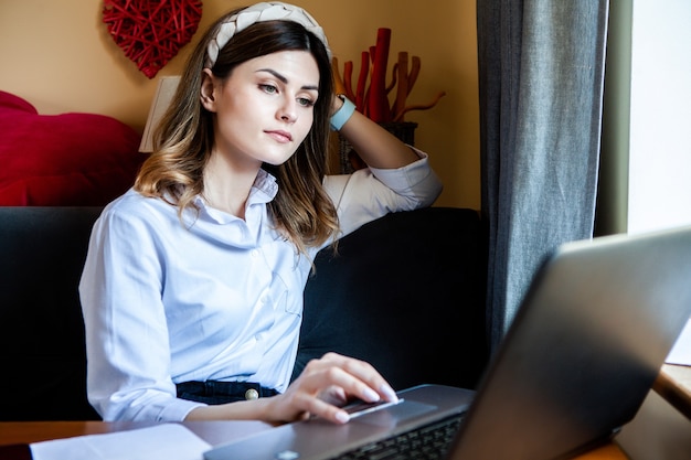 女の子はカフェのコンピューターで働いています。オンラインで働くフリーランサー