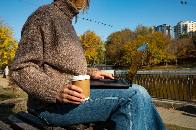 A girl works at a laptop in an autumn park