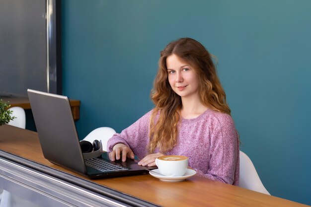 Girl works at laptop in a cafe bar