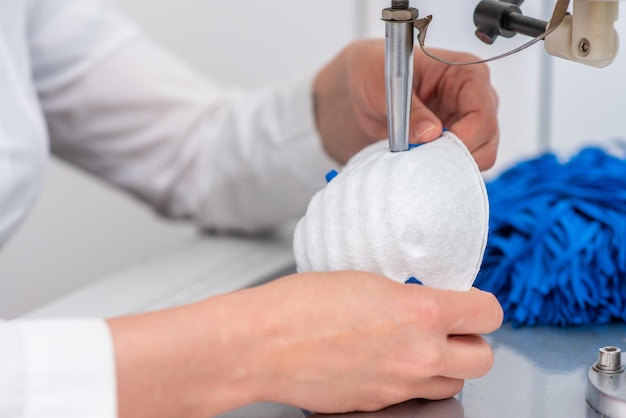 Photo the girl works at the machine for the manufacture of medical masks with nanofibre and solder the loops to them with ultrasound coronovirus and covid19 prevention