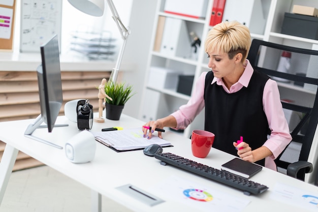 The girl works in the office with a marker and documents.