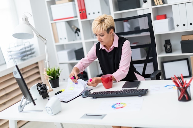 The girl works in the office with a marker and documents.