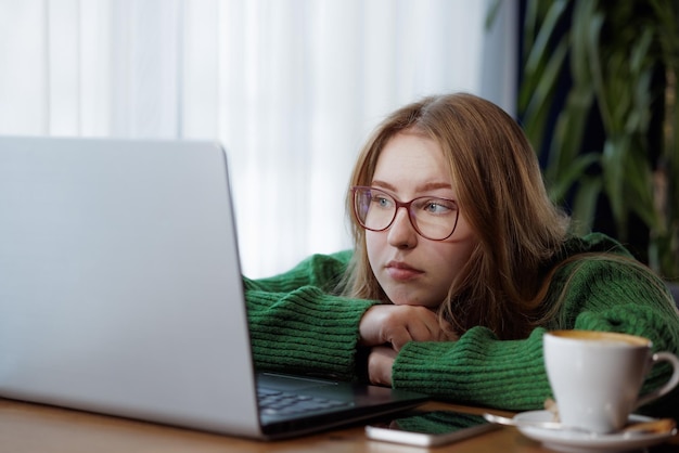 девушка работает в Интернете с ноутбуком и пьет кофе онлайн заказы