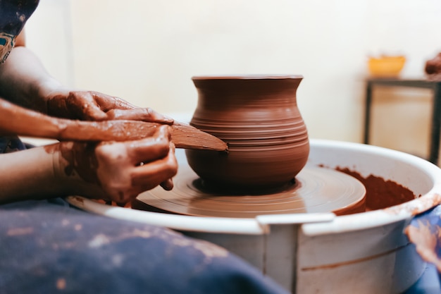 Girl works behind a pottery wheel forms a jug