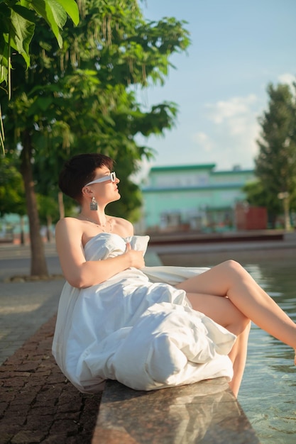 A girl wrapped in a blanket dips her feet into a pool enjoying outdoor relaxation and leisure