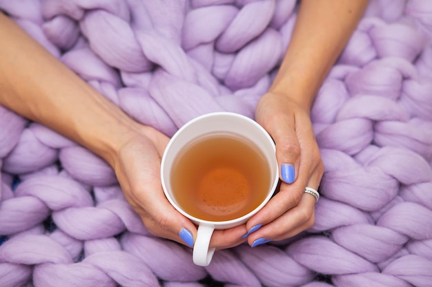 A girl wrapped in a large pink merino wool blanket a warm and very soft blanket a girl holding a cup of hot white tea top view