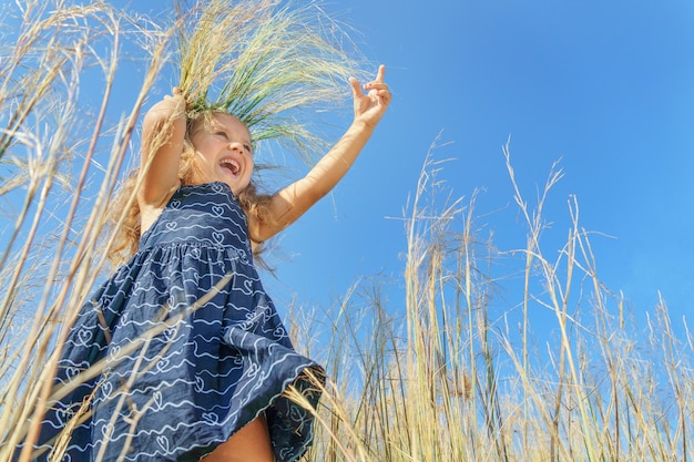 Girl in a wreath on a background of blue sky. happy child, happy childhood.