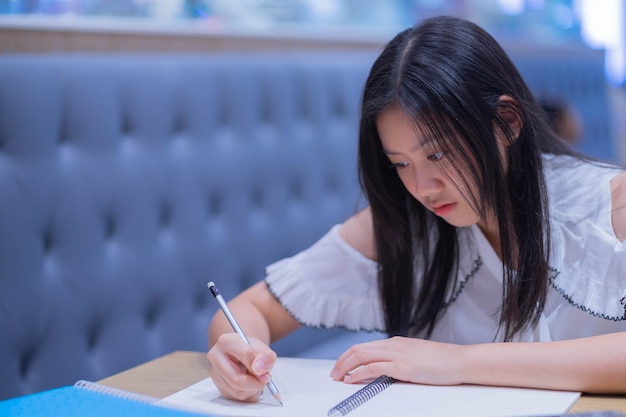 写真 テーブルに座って本を書いている女の子