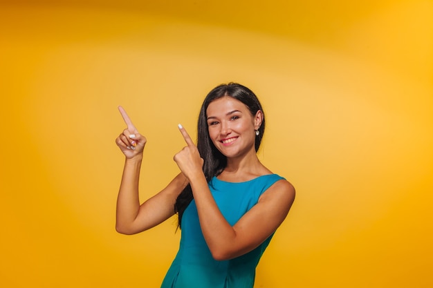 Girl on yellow background pointing finger