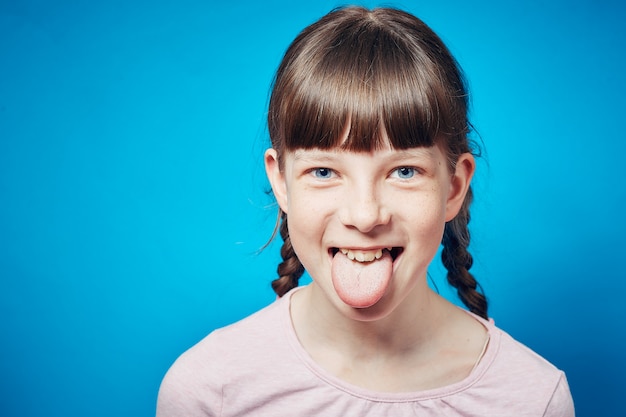 Girl on yellow background sticking tongue out. cute antics and frolicking concept