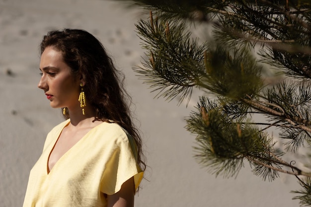 A girl in a yellow dress stands in front of a tree