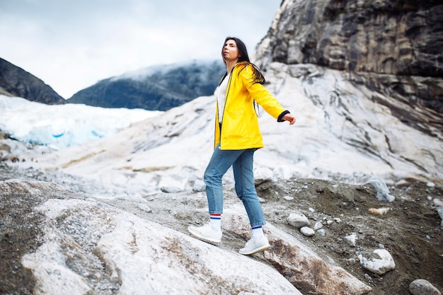노르웨이 산에서 야외에서 달리는 노란색 재킷을 입은 소녀 활동적인 여성은 자유를 즐긴다