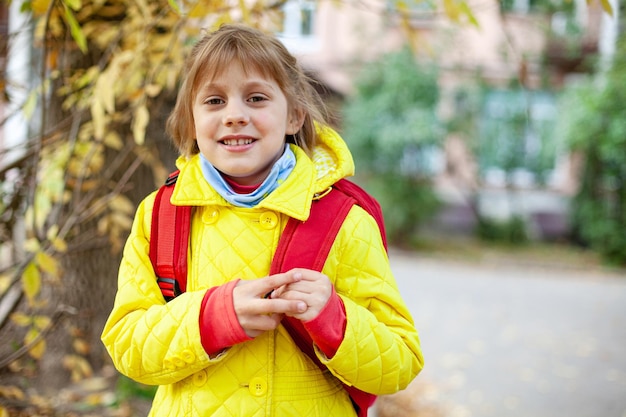 Girl in yellow jacket and with red briefcase on street in autumn