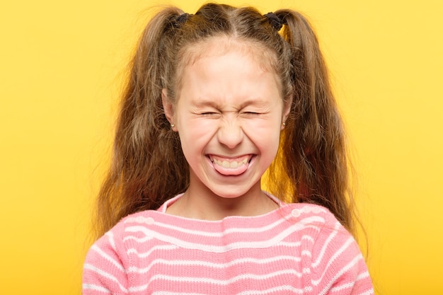 Girl on yellow sticking tongue out and laughing. cute antics and frolicking concept.