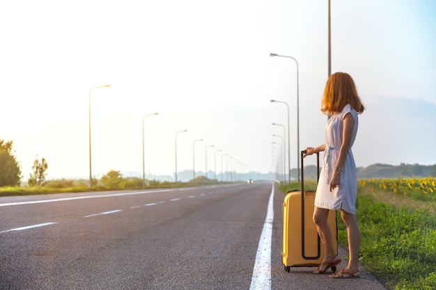 The girl and yellow suitcase at the  road