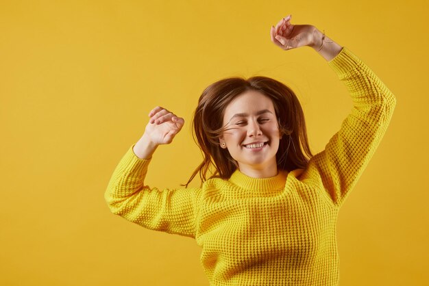 Girl in a yellow sweater dancing on a yellow background