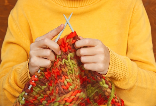 Foto ragazza in un maglione giallo lavora a maglia