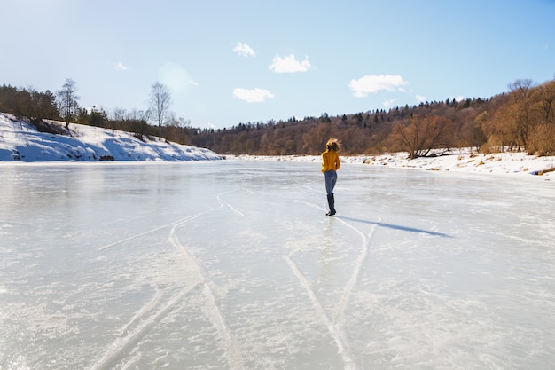 Girl in a yellow sweater and short haircut on the ice of the river.