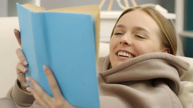 girl or young woman reading book lying down on sofa