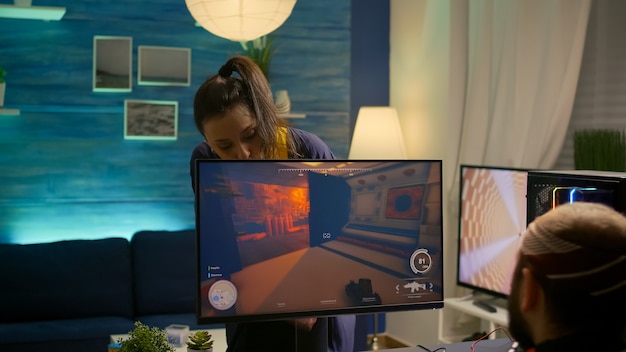 La ragazza spegne il computer del giocatore professionista durante il torneo in prima persona nello studio di casa di gioco. cyber player in streaming di videogiochi online utilizzando il potente desktop del sistema rgb in camera con luce al neon