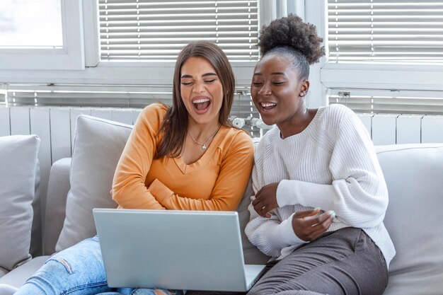 Photo girlfriend watching a very funny movie on laptop. smiling young women relaxing and watching movies at home, female friends having rest after hard week, copy space