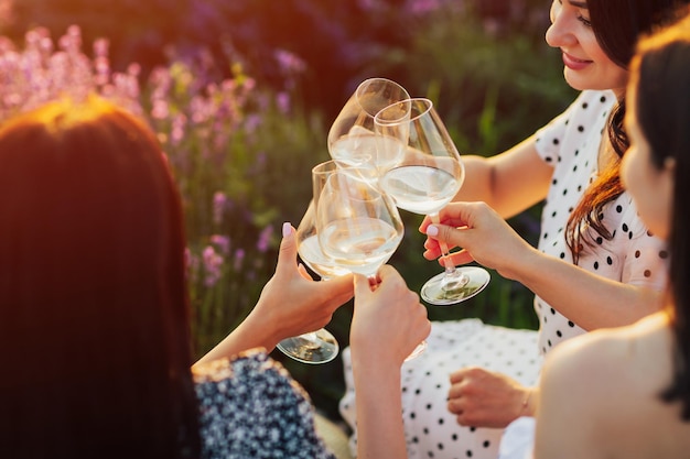 Fidanzate tintinnano bicchieri di vino seduti sul campo di lavanda