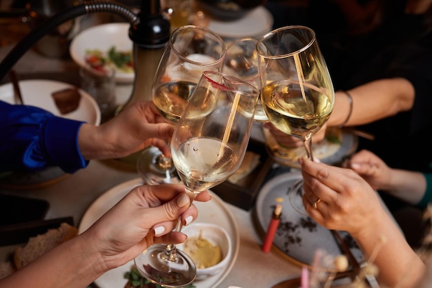 Girlfriends drinking wine and cheering while sitting in the bar Selective focus on glasses